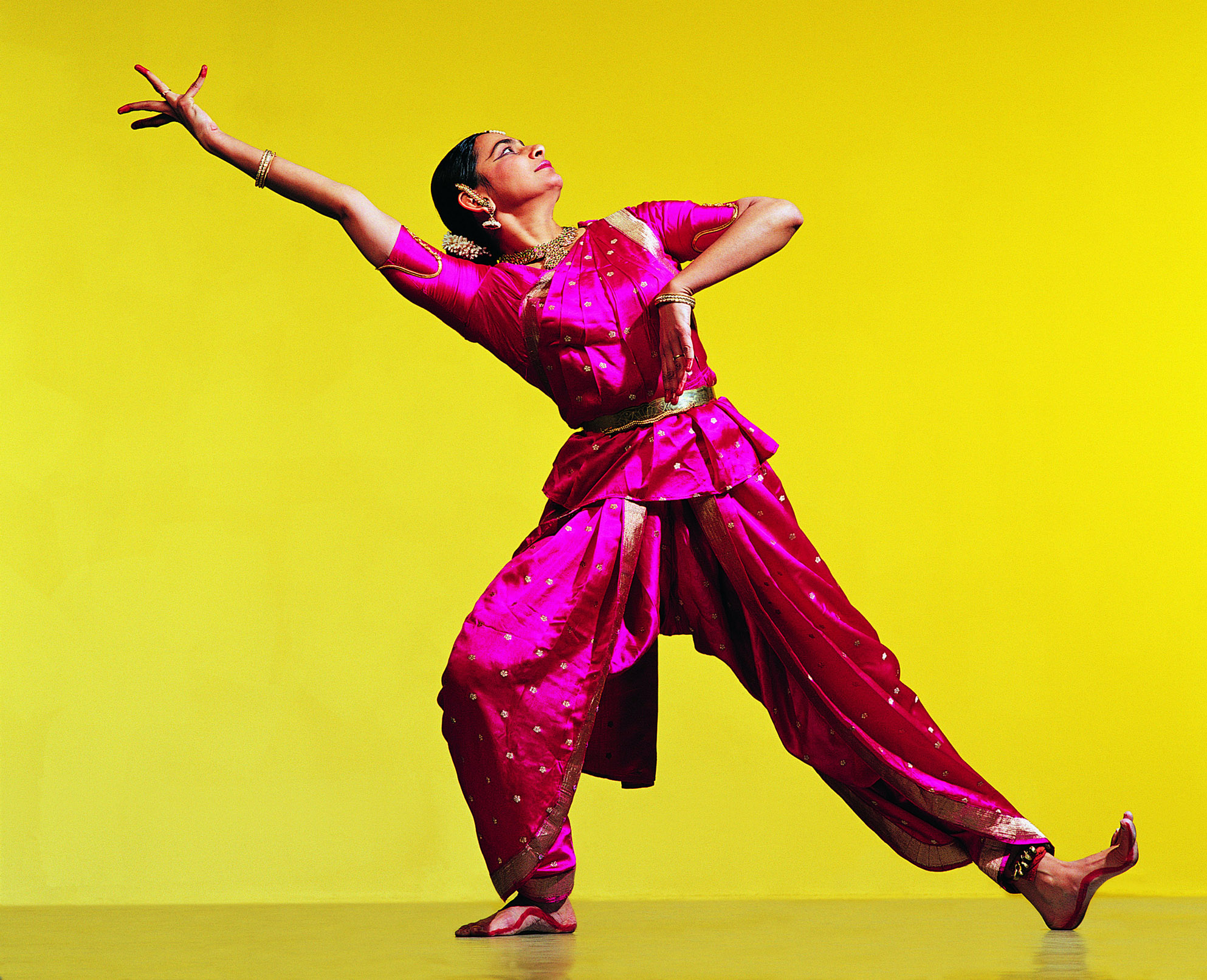 Woman in traditional Indian dress dancing on yellow background