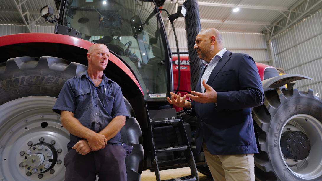Professor Harpinder Sandhu speaking with a farmer in front of a tractor