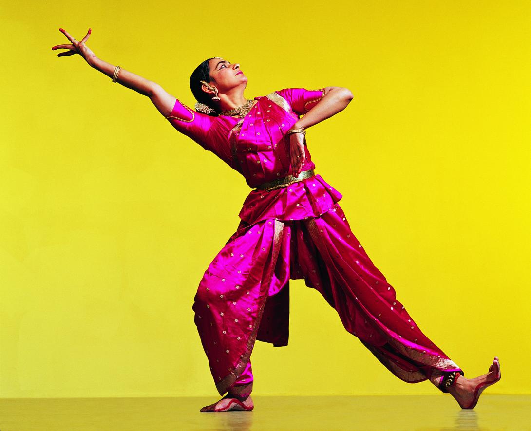 Woman in traditional Indian dress dancing on yellow background